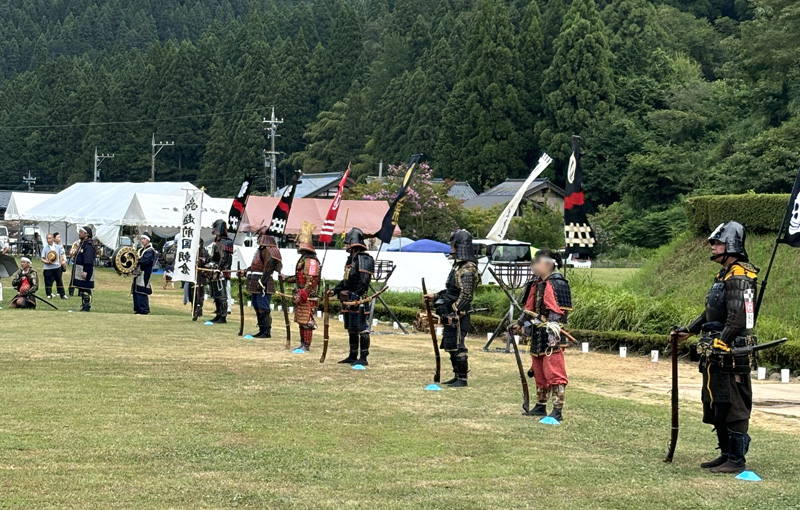 越前朝倉戦国まつりの武者隊列。甲冑姿の武者たちが旗指物を掲げて整列し、火縄銃の実演などが行われる。
