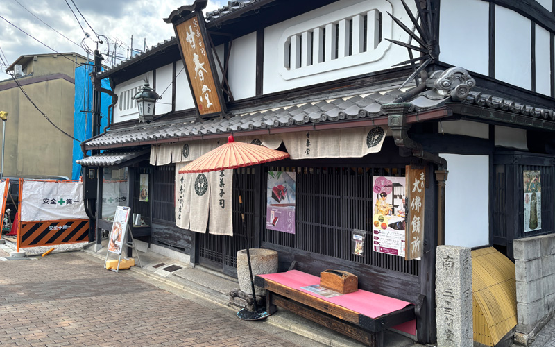 甘春堂 東店の外観。京町家風の建物に暖簾と朱色の傘