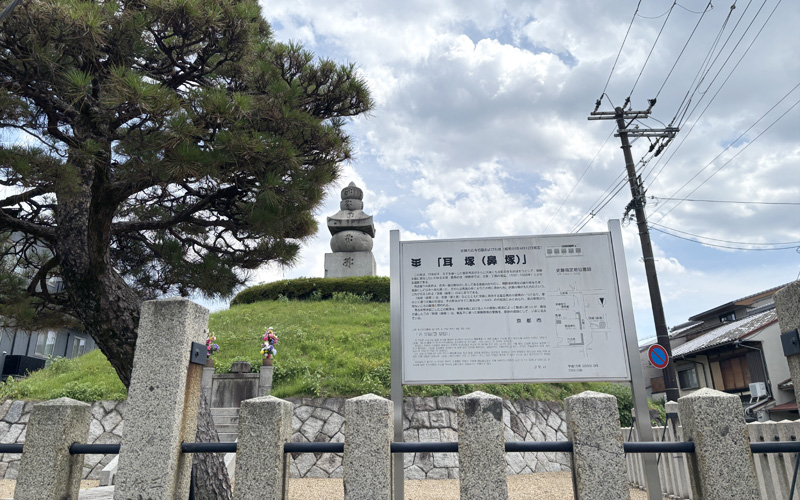 耳塚(鼻塚)。塚の上に五輪塔が立ち、手前に案内板がある